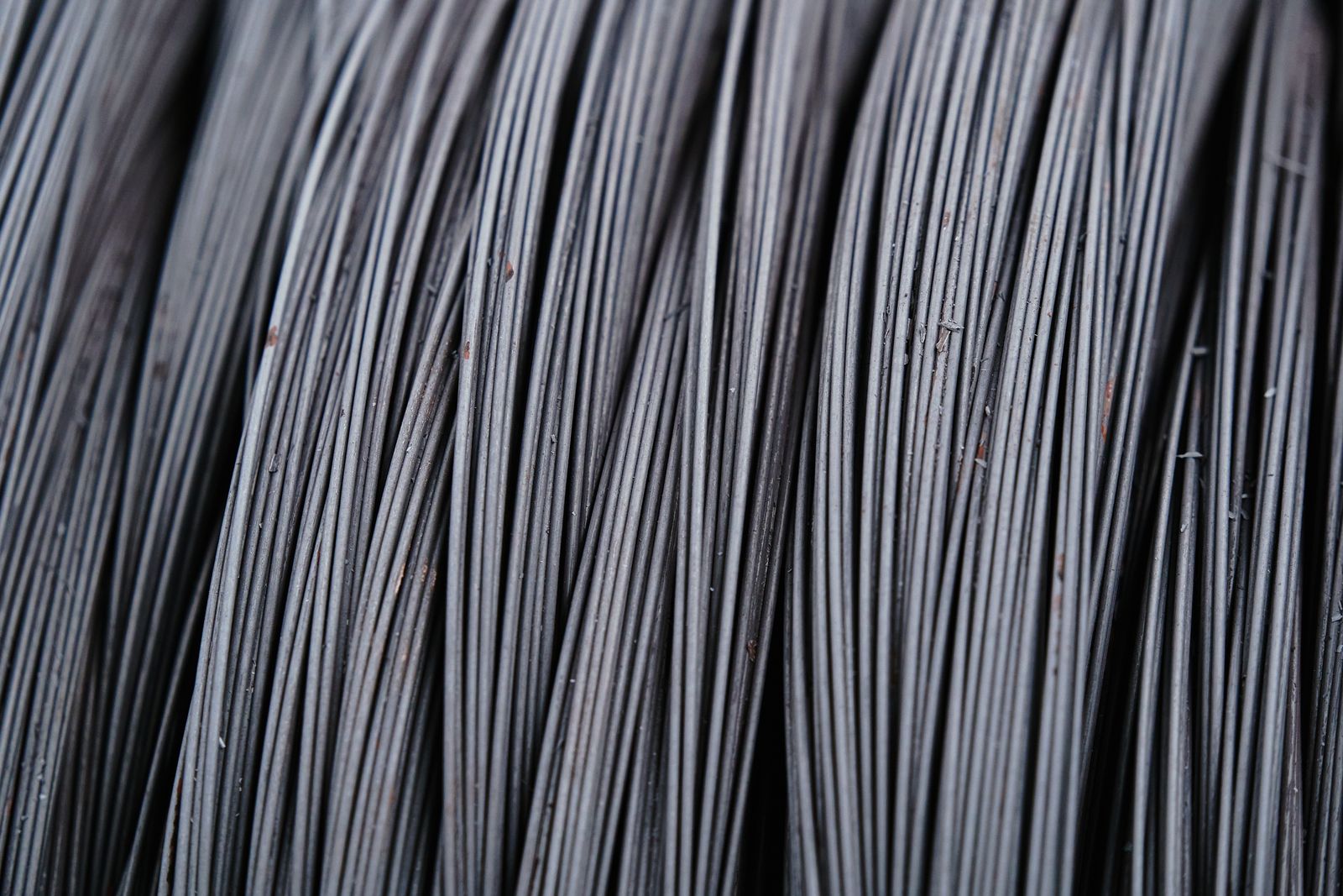 A close-up of tightly coiled grey wire, strands running diagonally across the frame