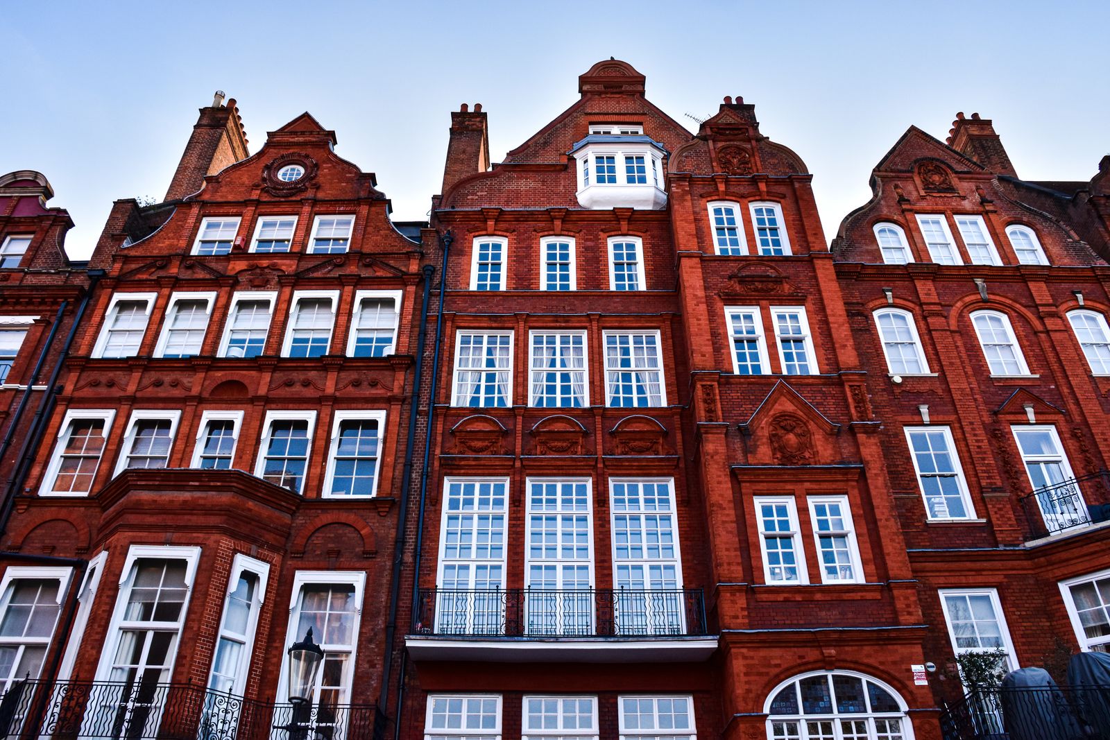 A red-brick mansion block with ornate gables and white sash windows