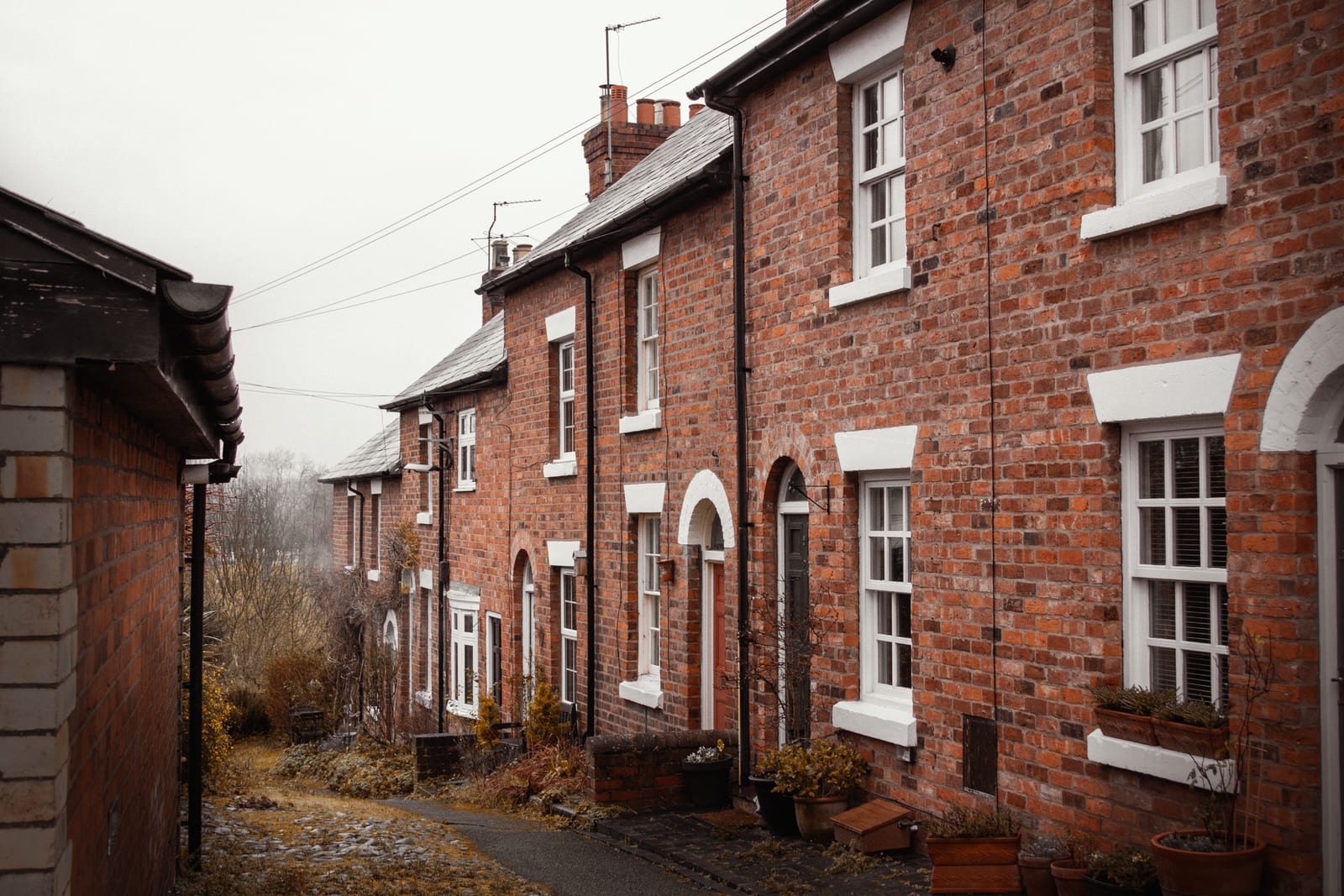 A plain red-brick terrace of houses under a flat overcast sky