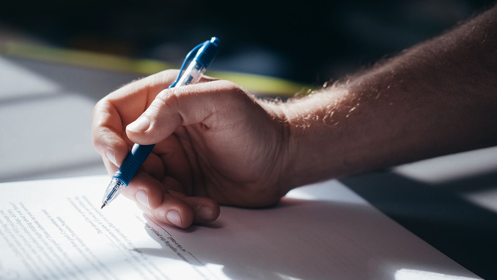 A hand signing a printed document with a fountain pen