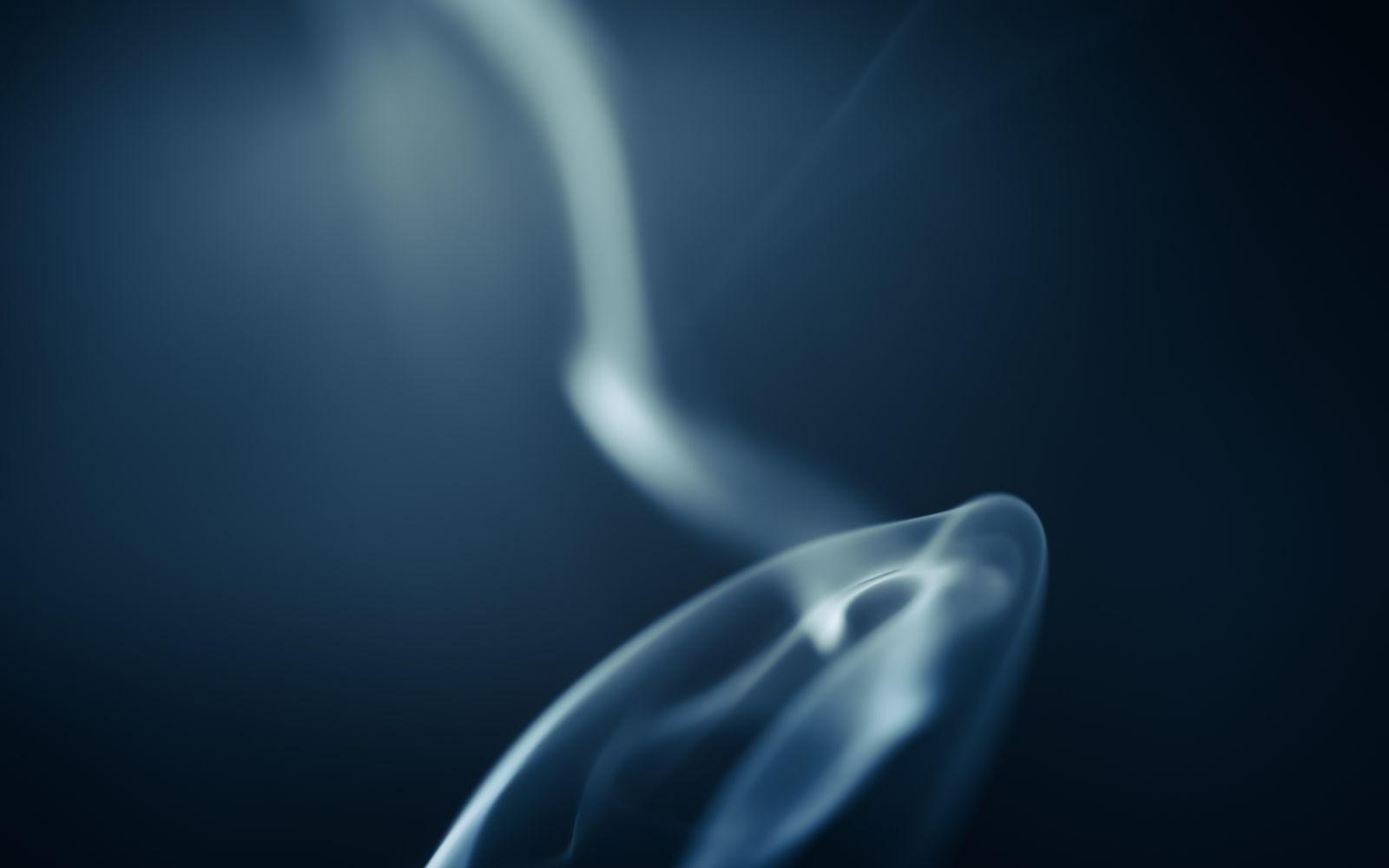 A single soft wisp of pale smoke curling against a dark navy background