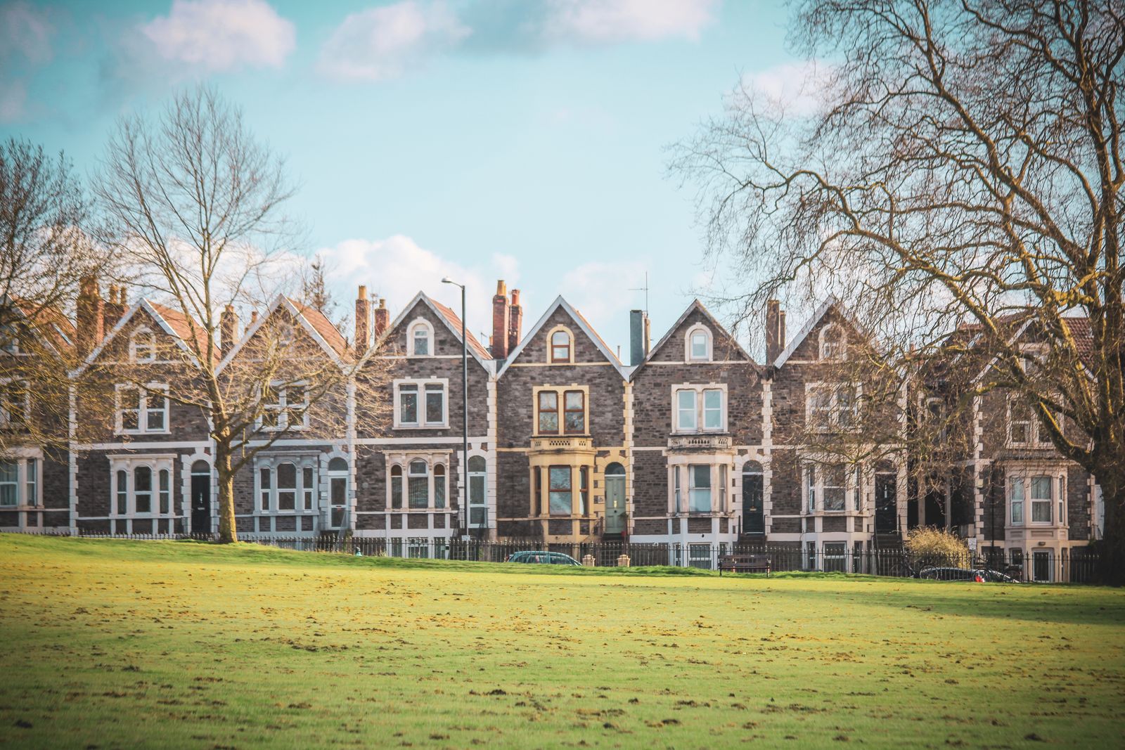 A row of Victorian terraced houses seen across an open green